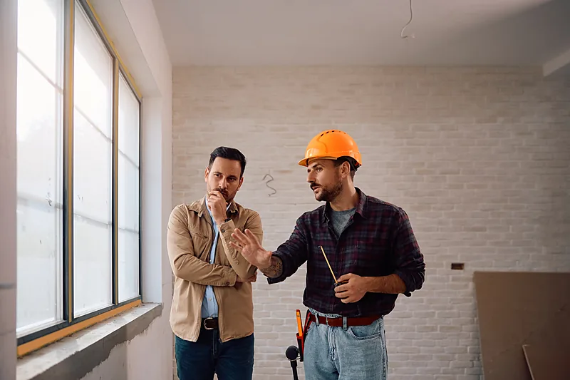 Estimator walking through an unfinished interior with a homeowner