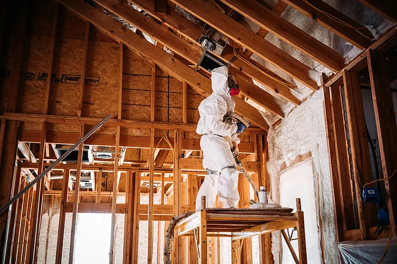 Spraying foam on a vaulted ceiling from a scaffold
